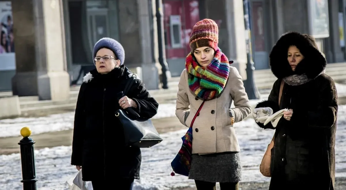Three pedestrians in winter hats and scarves walking together